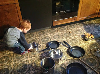 Kind räumt die Küchenschränke aus: Töpfe, Pfannen, Kochlöffel
