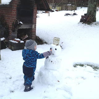 So viel Schnee: Das Kind baut seinen ersten Schneemann und steckt ihm eine Möhre als Nase an.
