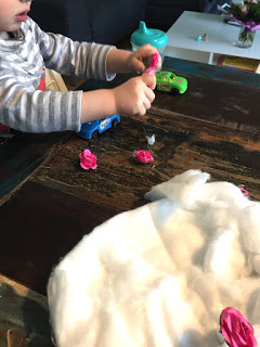 Das Kind steckt kleine Plastikblumen in die Baumwollwatte