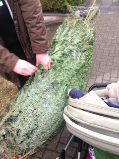 Der Mann und das Kind freuen sich über den noch verpackten Weihnachtsbaum und bringen ihn nach Hause