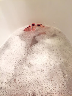 Ich liege in der Badewanne und genieße ein Schaumbad. Man sieht meine Füße.