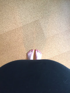 Blick von oben: Der Schwangerschaftsbauch und die Füße